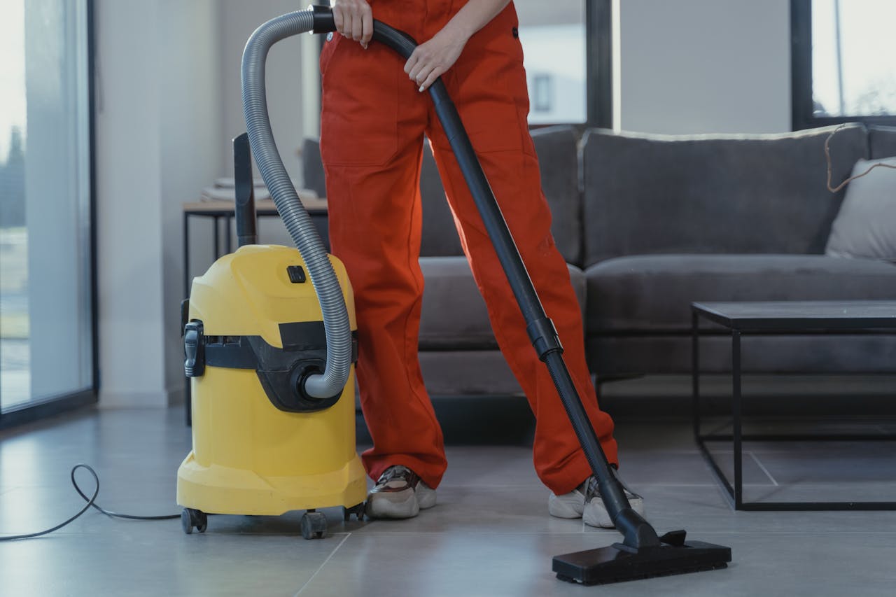 The Art of Drawing Readers In: Your attractive post title goes here A professional cleaner in red coveralls vacuums a contemporary living room with a yellow vacuum cleaner.